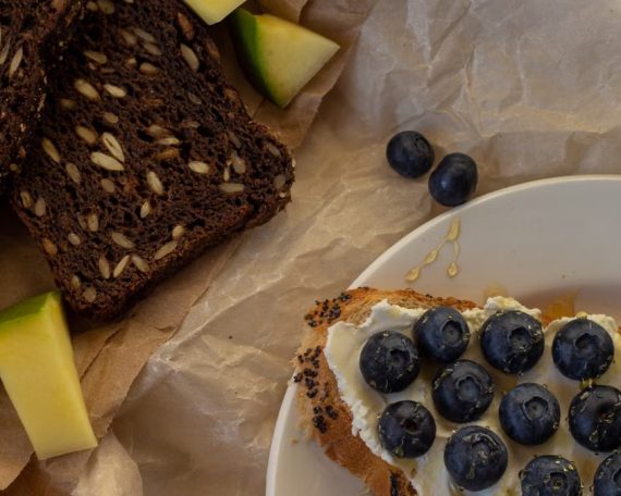 A vibrant spread of seeded bread, blueberries, and honey. Perfect for breakfast.